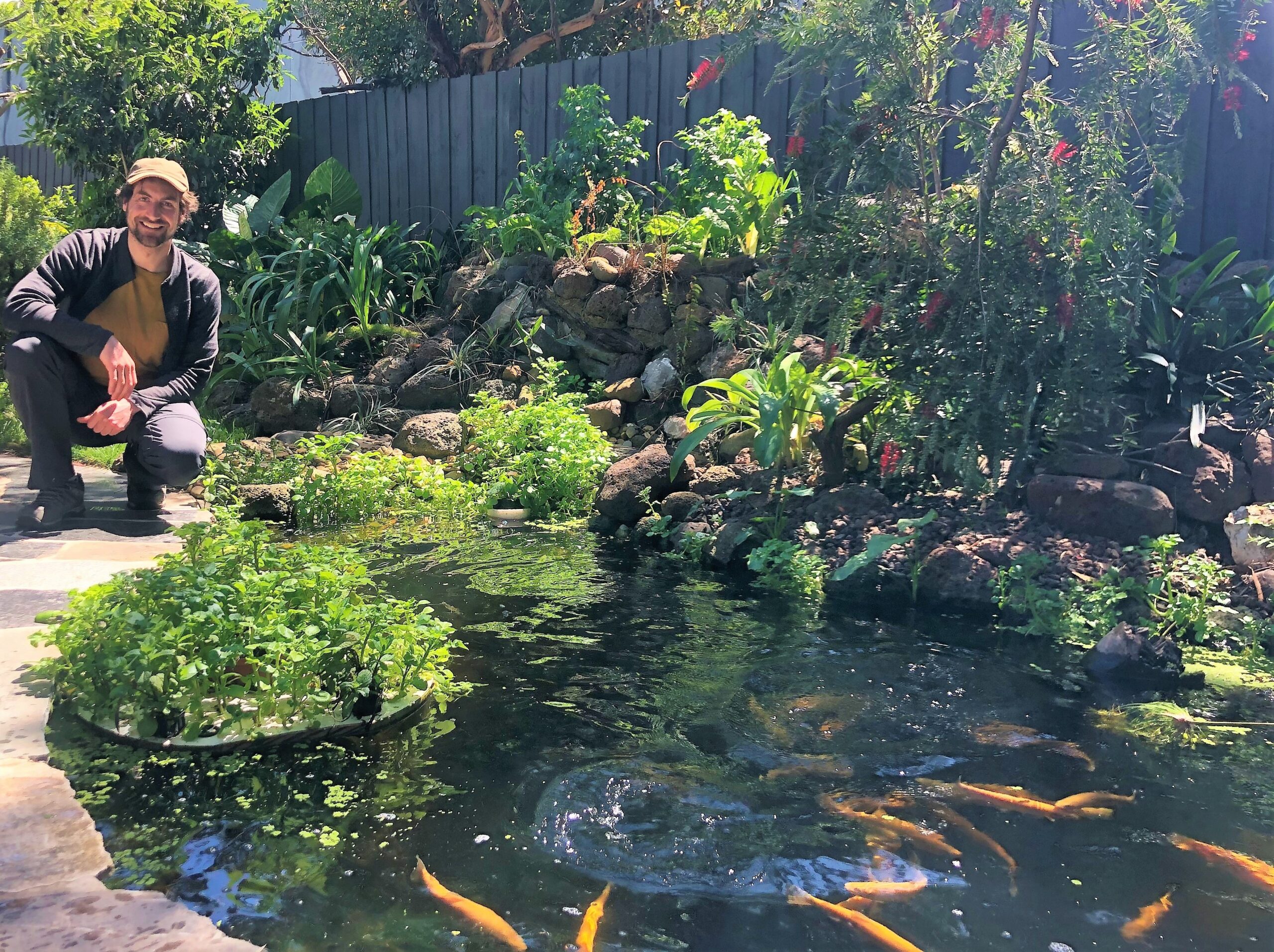 Jonathan Martinetto at his holistic aquaponics pond system with goldfish and lush plants